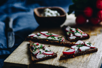 Rye bread with cottage cheese fresh radish and chive. Wooden tray.