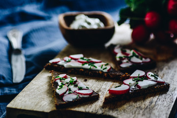 Rye bread with cottage cheese fresh radish and chive. Wooden tray.