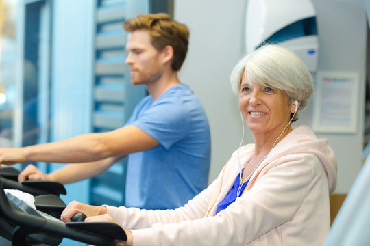 elderly lady and young man using treadmill