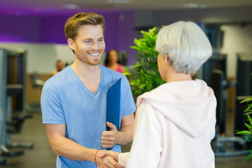man with clipboard greeting woman at fitness center