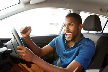 Excited young african american man driving a car