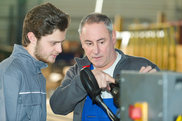 young factory worker being taught how to use machinery
