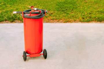 big red fire extinguisher on wheels with a black hose