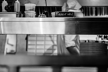 Retro restaurant kitchen close up with Reserved table and a chief cook on the background. Black and white