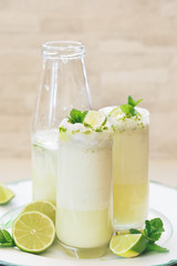 Coconut Lime Beverage in glasses and bottle, selective focus