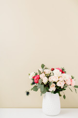 Beautiful flowers bouquet in flowerpot in front of pale pastel beige wall. Floral lifestyle composition.