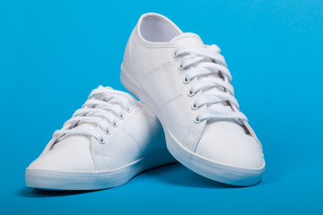 Pair of new white sneakers on blue background