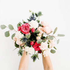 Girl's hands holding beautiful flowers bouquet: bombastic roses, blue eringium, eucalyptus, isolated on white background. Flat lay, top view. Floral composition