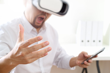 businessman wearing virtual reality goggles in modern office with mobile phone using with VR headset
