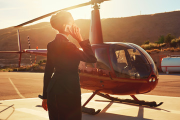 Business woman talking by phone near the helicopter © Alex Tihonov