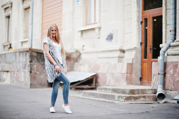 Fototapeta na wymiar Stylish blonde woman wear at jeans and girl sleeveless with white shirt against street. Fashion urban model portrait.