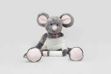Stuffed animal with arm bandage on grey background