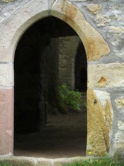 Pforte einer Kirchenruine mit alter Linde im Innenraum