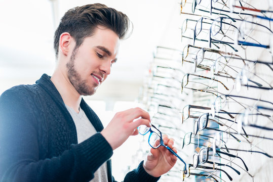 Man In Front Of Shelf With Glasses In Optician Shop