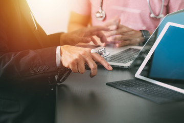 Medical co working concept,Doctor working with smart phone and digital tablet and laptop computer to meeting his team in modern office at hospital