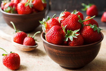 Fresh strawberry in a bowl on a wooden background