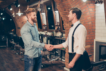 Great job! Happy satisfied client in a barber shop. Red bearded young man got a stunning hairdo and his beard got cutted perfectly