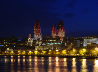 Baku night cityscape with flaming towers and reflections in the Caspian sea bay