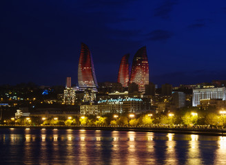 Fototapeta na wymiar Baku night cityscape with flaming towers and reflections in the Caspian sea bay