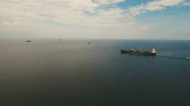 Aerial view Cargo ships in the Bay of Manila. Large container ship in the sea. Flying over the water surface of the sea with ships, blue sky and clouds. 4K video. Aerial footage. Philippines, Manila.