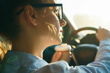 Woman with coffee to go driving her car