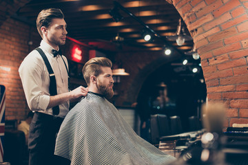 Great job! Hairstylist and a client in a barber shop. Red bearded young man got a stunning hairdo...