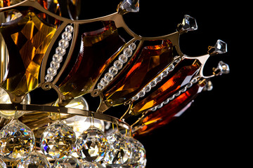 Contemporary gold chandelier isolated on black background. Crystal chandelier decorated amber...