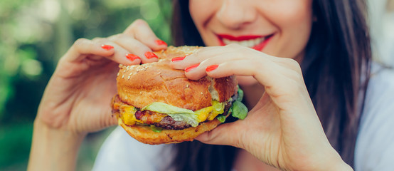 Happy young woman eat tasty fast food burger - obrazy, fototapety, plakaty