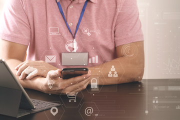 businessman in pink t-shirt working with smart phone and digitl tablet computer on wooden desk in modern office with virtual icon diagram
