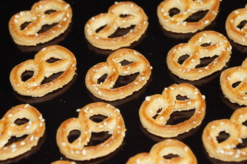 Sweet pretzel sprinkled with sesame seeds isolated on a black background