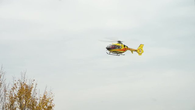 Lublin, Poland - Nowember 2016: Yellow helicopter taking off against a grey sky. Long shot.