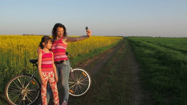 Happy mother with her baby taking pictures in nature. Cyclists are photographed.