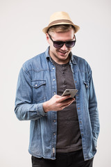 Happy young man smiling while using mobile phone on white