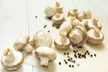 Fresh organic mushrooms and pepper peas on a white wooden background.