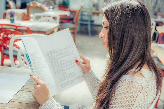 Beautiful Woman Looking At Menu And Ordering Foods In Restaurant