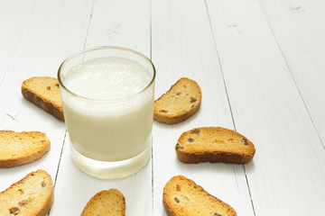 Healthy food, sour yogurt in a glass cup and crackers with raisins on a white table, space for text.