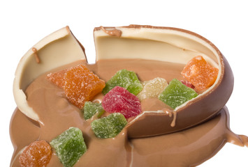 Broken chocolate egg filled with liquid hot milk chocolate and dried fruits 