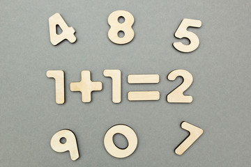 An example of wooden figures: one plus one is two on a gray background background.