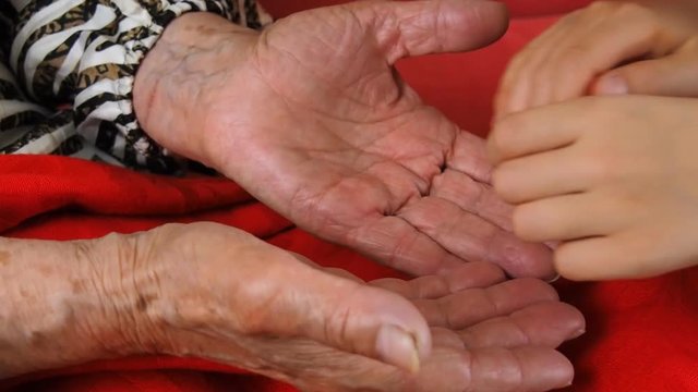 Hands of an old man. A child strokes the hands of an elderly person.