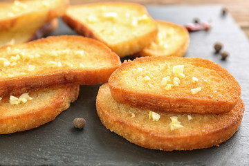 Tasty garlic French bread slices on slate board