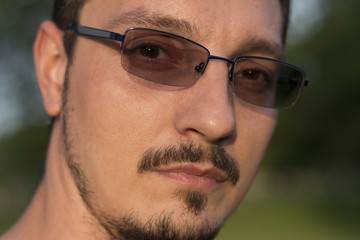 Young guy wearing eyeglass with photo sensitive lenses, close up shot of his face only
