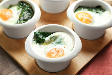 Bowls with tasty eggs and spinach, closeup