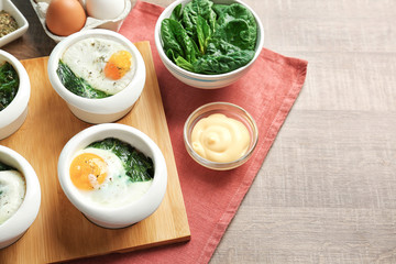 Bowls with tasty eggs and spinach on wooden table