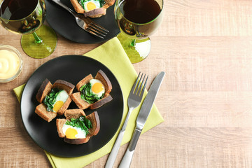 Plate with tasty eggs and spinach on wooden table
