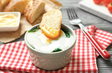 Bowl with tasty egg and spinach on wooden table