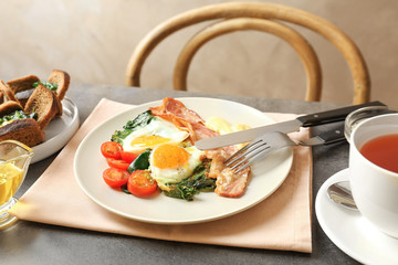 Plate with tasty eggs, spinach and bacon on table