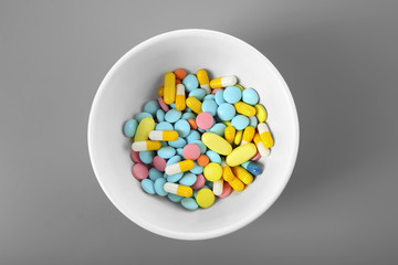 Diet concept. Bowl with colorful assorted pills on color background