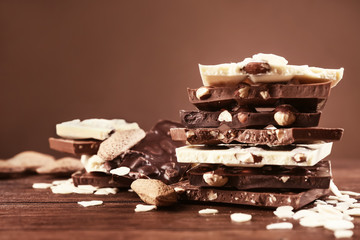 Milk, dark and white chocolate with almond nut on brown background