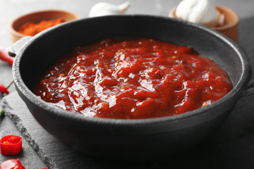 Pan with tasty chili sauce on table, closeup