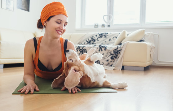 Woman has yoga practice at home but dog try to play with her